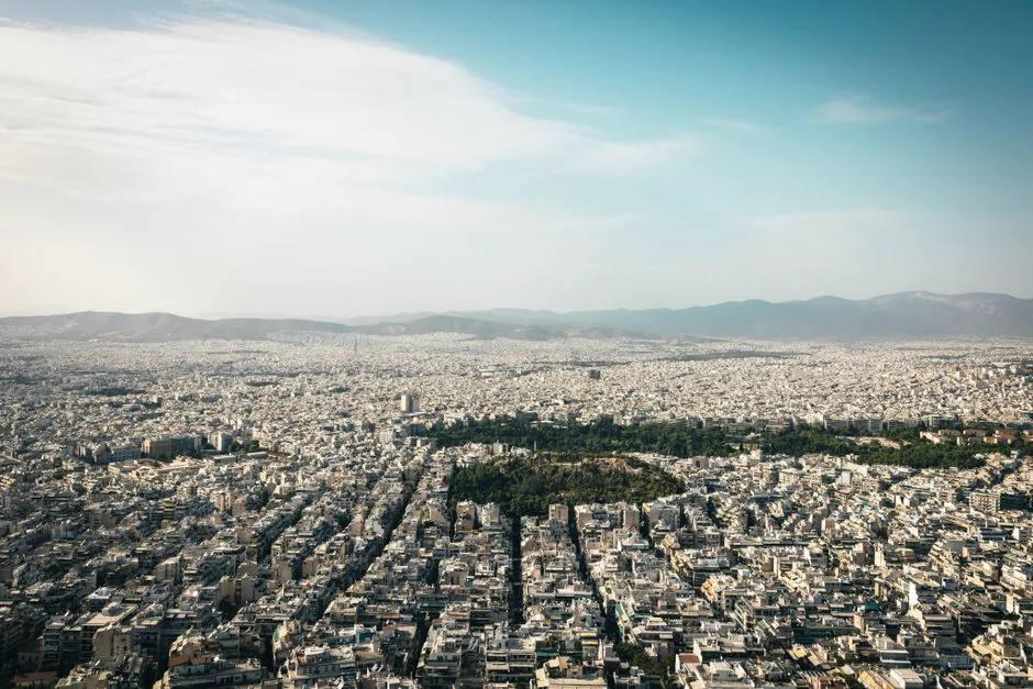 Aerial view of Athens cityscape showcasing urban density with mountains in the background.
