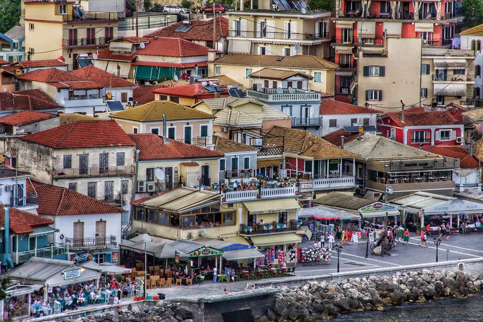 A vibrant aerial view of Parga, Greece, showcasing colorful rooftops and bustling seaside cafes.