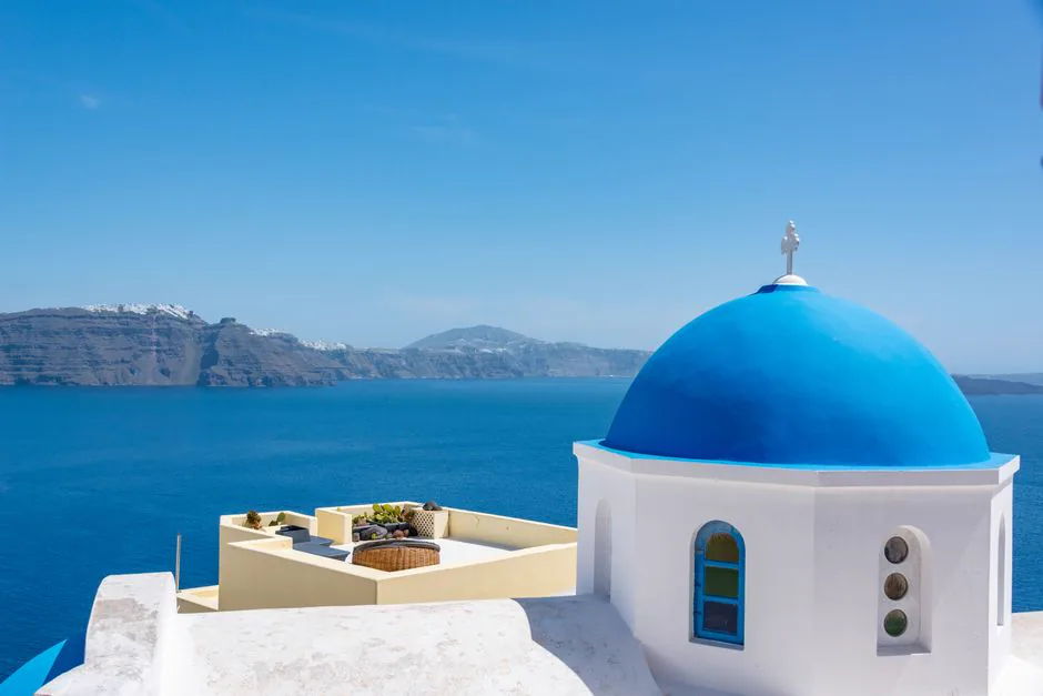 Iconic blue dome church in Santorini with a stunning view of the Aegean Sea.