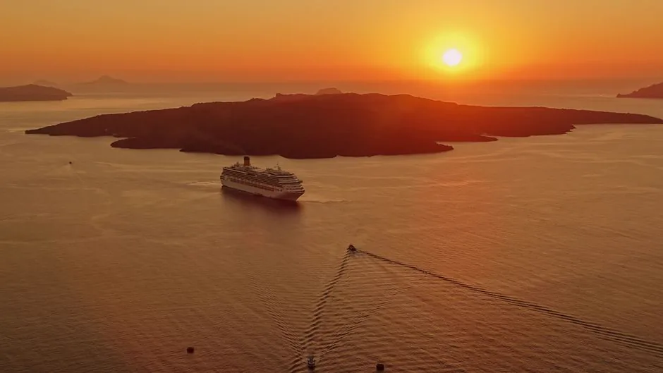 A breathtaking sunset view of a cruise ship near the island of Santorini, Greece.