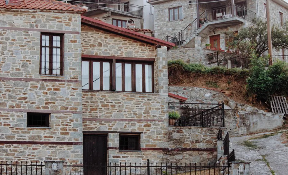 Rustic stone houses on a hillside in Kleisoura, Greece with traditional architecture.