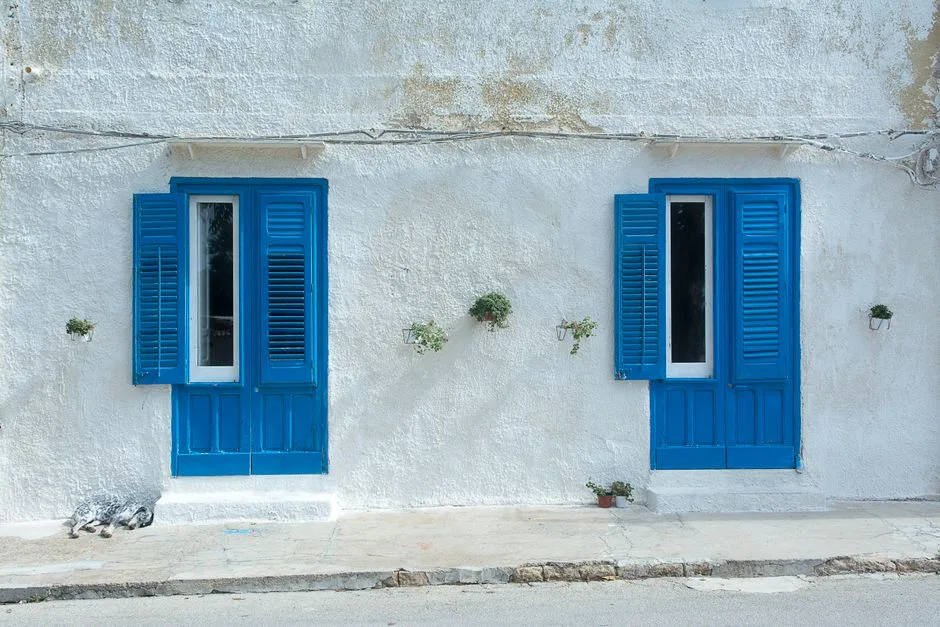 Mediterranean building with blue shutters and whitewashed walls.
