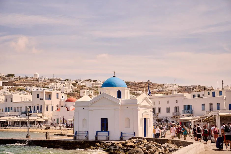 Explore the picturesque Agios Nikolaos Church by the sea on a sunny day in Mykonos, Greece.