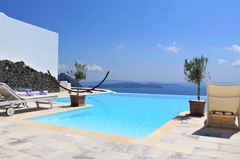 Relax by a serene infinity pool overlooking the Aegean Sea in Santorini, Greece.