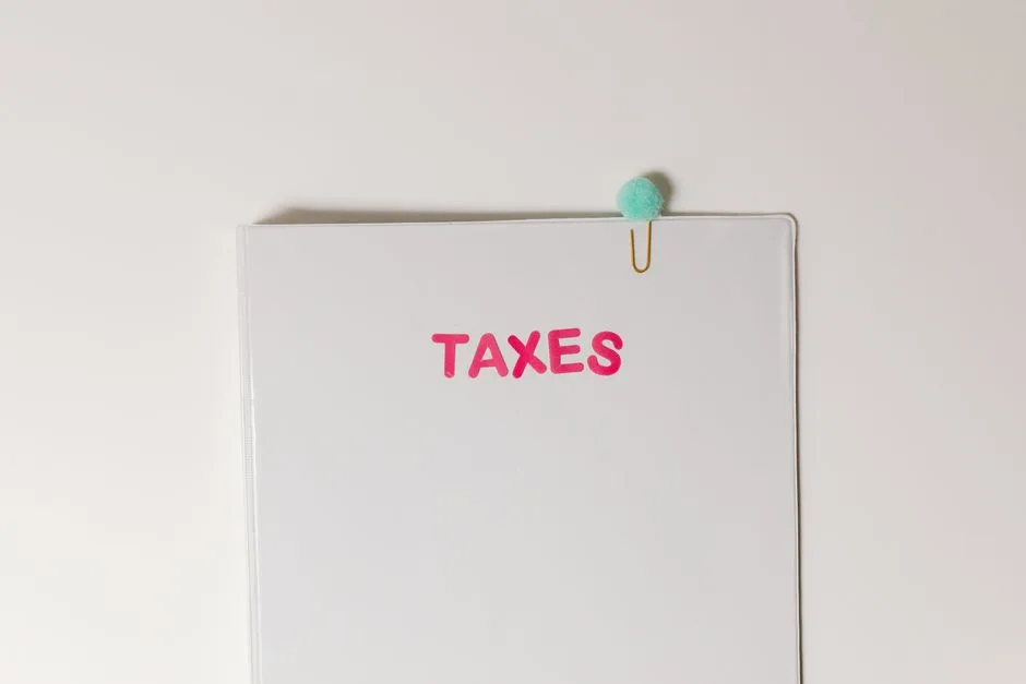 Close-up of a tax file with a pink 'TAXES' label and a paperclip, offering copy space and a conceptual minimalist design.
